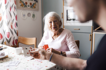 An elderly woman playing cards with a person
