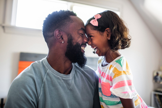 A man and his child with their faces touched together, both smiling